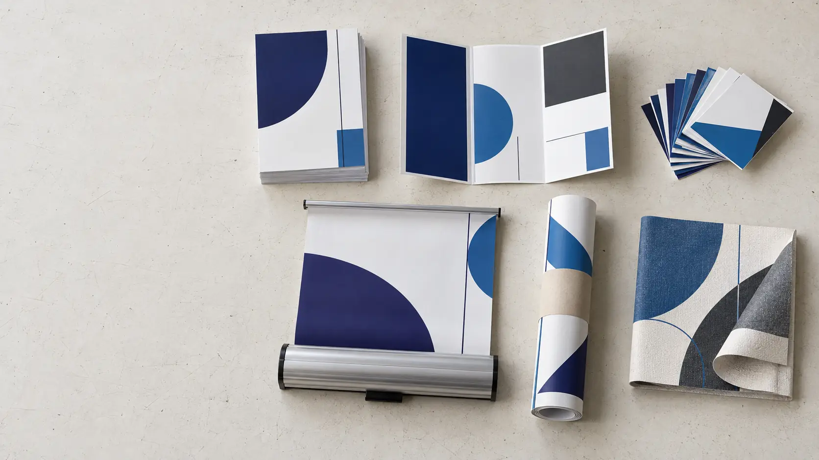 Flyers, a brochure, business cards, a roller banner, a poster and wallpaper laid out on a bench